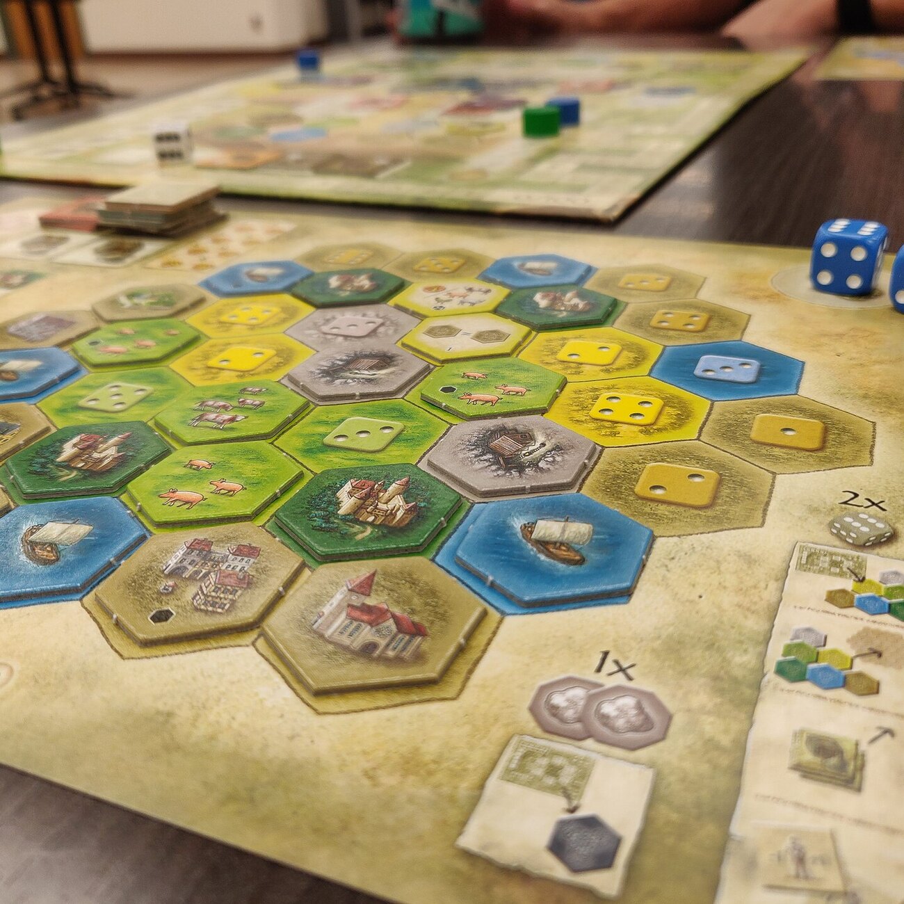 Candlemark Manor board game in play with warm lamp light, tokens, and hands at the table